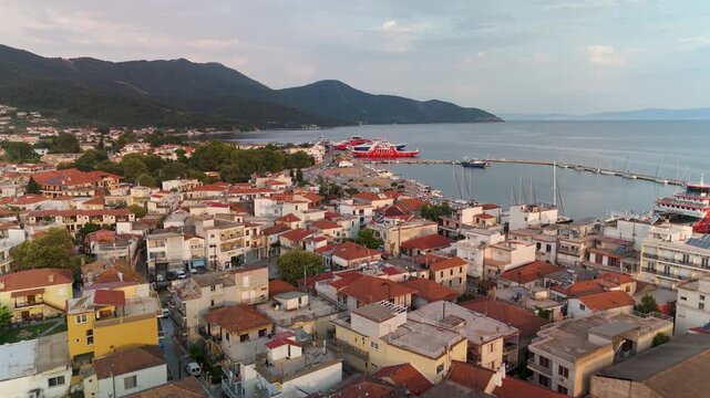 Golden sunrise aerial drone flight over the rooftops and harbor of Limenas town, the picturesque capital of Thasos Island, Greece.