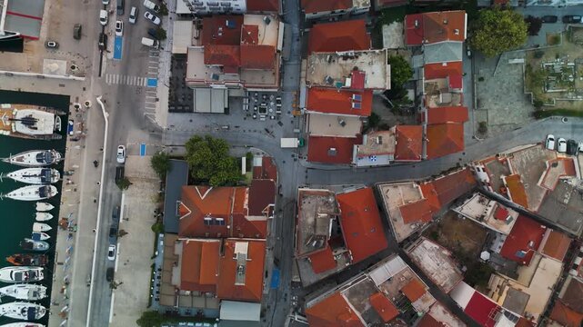 Vertical top-down aerial drone view of Limenas, Thasos Island, Greece, capturing the picturesque harbor, coastal town architecture, and deep blue Aegean Sea.