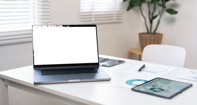 Laptop mockup with blank white screen on a bright office desk with a coffee cup, calculator, and vase. Minimalist workspace with ample copy space. - Powered by Adobe