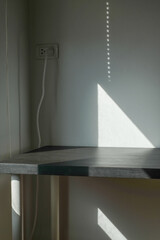 Empty white cement wall room and black table with shadow from window.