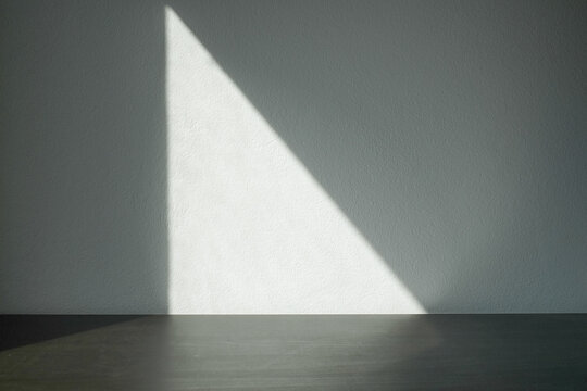 Empty white cement wall room and black table with shadow from window.