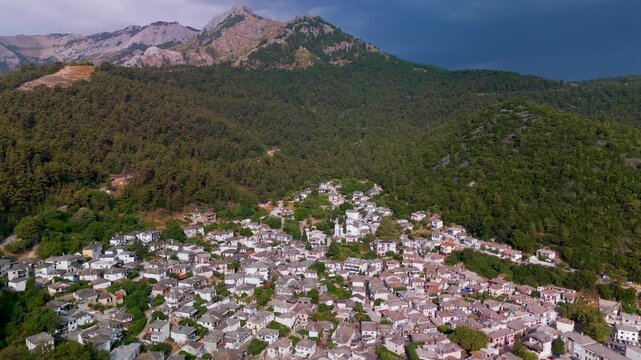 Scenic high altitude aerial pan over the traditional Greek mountain village of Panagia on Thasos Island, Greece, highlighting the forested slopes of Mount Ipsarion.