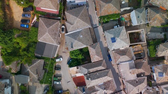 Vertical top-down aerial drone view over the traditional stone rooftops of Panagia village, nestled on the slopes of Mount Ipsarion, Thasos Island, Greece.