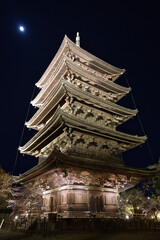 Fototapeta premium 漆黒の夜空に浮かぶ月と、幻想的にライトアップされた東寺・五重塔の静謐な夜景