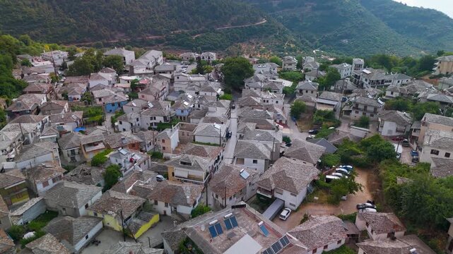 Aerial drone tracking shot flying over the historic traditional stone houses of Panagia village, situated on the green forested massif of Mount Ipsarion, Thasos, Greece.