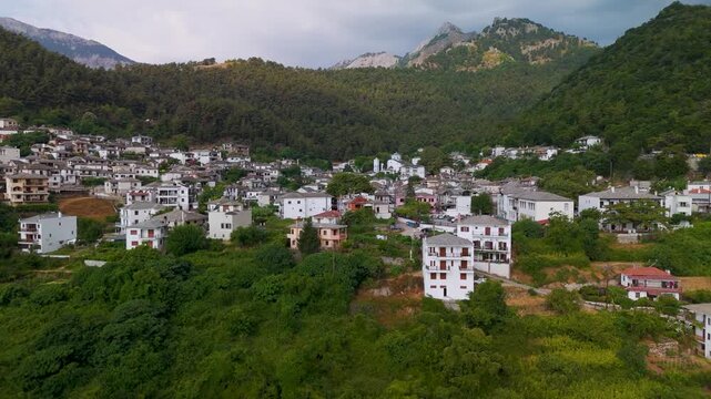 High aerial drone establishing shot approaching the traditional Greek mountain village of Panagia, nestled on the eastern forested massif of Mount Ipsarion, Thasos Island.