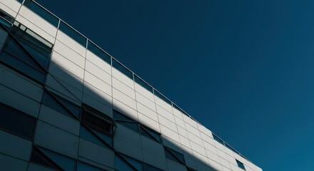 Obraz premium Sunlight illuminating geometric angles and reflective glass panels on a towering contemporary structure, creating striking patterns of shadow and light, pattern, Architecture, surface