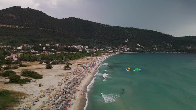 Scenic aerial drone tracking shot gliding over the pristine Golden Beach coastline and the clear turquoise waters of the Aegean Sea bay, Thasos Island, Greece.