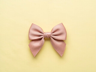 Soft pink fabric bow isolated on yellow background with minimal flat lay composition gift decoration and feminine design