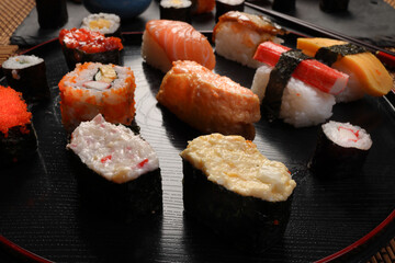 High-quality close-up of fresh assortment sushi rolls served on a dark plate, featuring vibrant colors, fresh fish, laid on slate board bamboo mat chopsticks