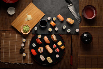 High-quality close-up of fresh assortment sushi rolls served on a dark plate, featuring vibrant colors, fresh fish, laid on slate board bamboo mat chopsticks
