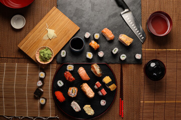 High-quality close-up of fresh assortment sushi rolls served on a dark plate, featuring vibrant colors, fresh fish, laid on slate board bamboo mat chopsticks