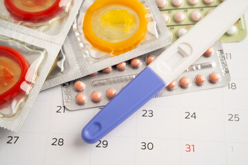 Pregnancy test and birth control pills on calendar, contraception health and medicine.