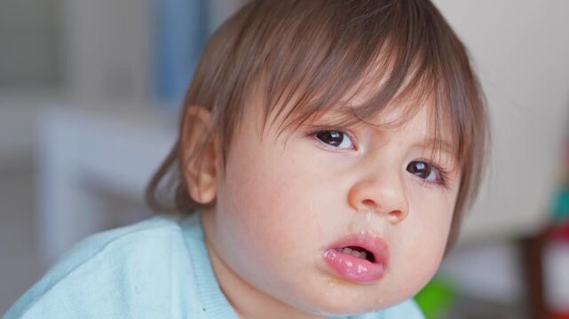 Image of a young boy with a runny nose and watery eyes, displaying signs of a cold, flu, or allergies as he gazes at the camera while seated inside his home