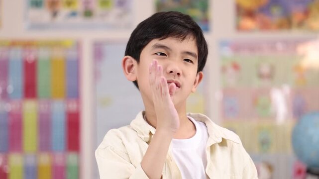 Asian Schoolboy Reacting to Unpleasant Smell in Classroom