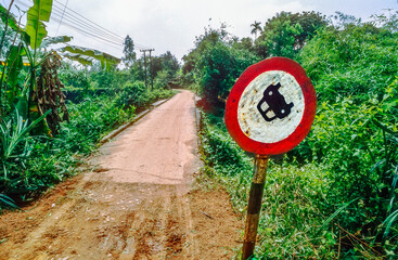 Historisches Farbfoto einer humoresken Szene eines auf dem Kopf stehenden Autos auf einem vVerbotsschild an einer schmalen, unbefahrenen Landstra&szlig;e im Dschungel Vietnams, 23.M&auml;rz 1994
