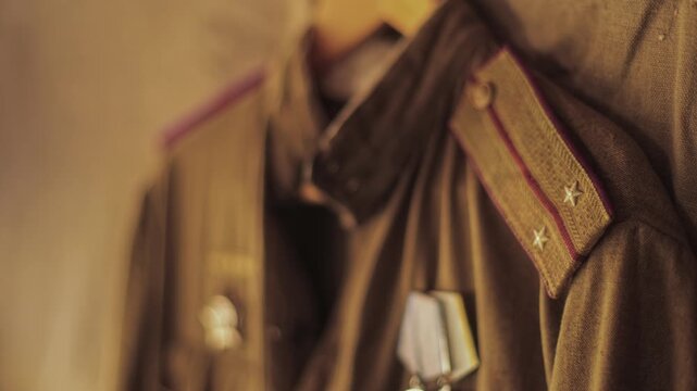 Close-up of vintage Soviet military uniform, shoulder straps of Red Army officer, lieutenant rank, combat medals pinned on jacket, representation of historical wartime apparel. Great Patriotic War ear