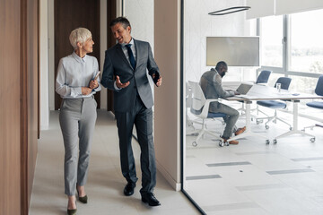 Professional Colleagues Walking and Talking in a Modern Office Corridor During a Morning Visit