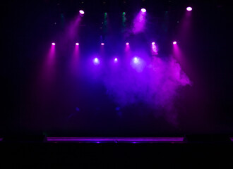An empty stage of the theater, lit by spotlights and smoke before the performance