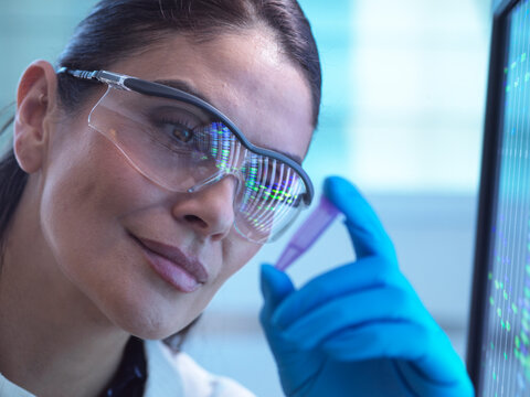 Scientist analysing DNA samples in laboratory with gloves and glasses