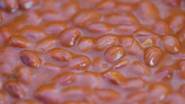 Close up red beans texture showing glossy cooked azuki paste with whole beans, warm brown tones, moist surface, appetizing cozy vibe for culinary backgrounds and packaging
