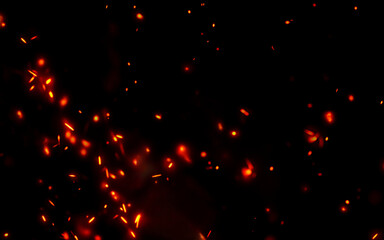 Orange glowing embers flying in air against dark background creating cinematic spark effect for overlay design and creative digital art compositions
