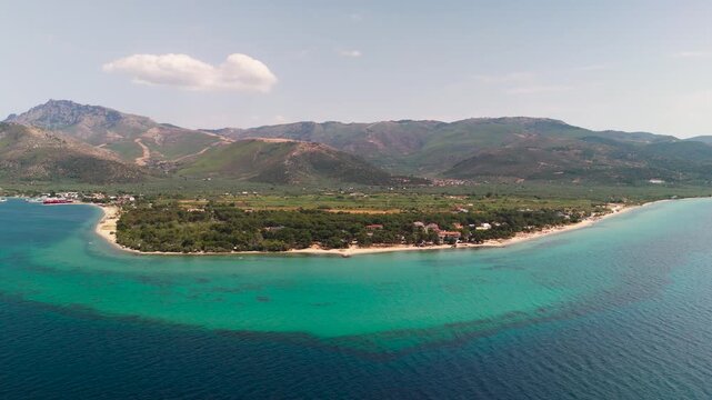 Aerial Circling Shot Over Prinos Port and Beach, Thasos, Greece, Highlighting the Turquoise Aegean Sea, White Sand, and Lush Green Coastal Forest.