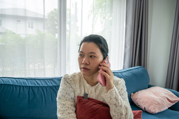 Asian Woman Talking Seriously on a Pink Smartphone Near a Bright Window