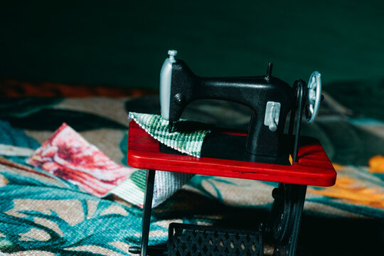 Toy sewing machine working with fabric on bold red tabletop