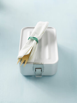Reusable lunchbox with a napkin wrapped fork on light background