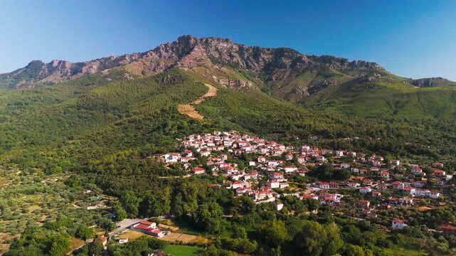 Sweeping Aerial Pan Across Verdant Mountain Slopes and the Historic Village of Kallirachi, Thasos, Greece, Under Blue Summer Sky.