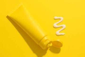 Yellow tube of cream on bright yellow background with white squiggle