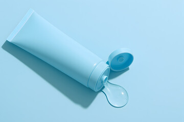 Light blue tube of cream or lotion with cap off on pastel background