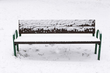 Snowy park bench winter. Empty wooden bench in snow. Cold quiet outdoor scene. White background landscape. Lonely seat in park. Winter minimal composition. Calm frozen morning view.