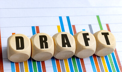 Wooden round blocks with word draft on colorful bar chart background, symbolizing business planning, data analysis