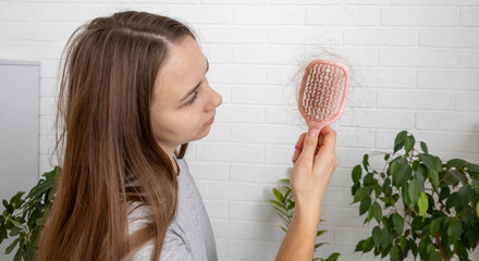 Woman holding pink hairbrush with fallen hair, hair loss problem