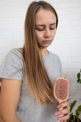 Woman holding pink hairbrush with fallen hair, hair loss problem