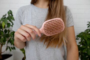 Woman holding pink hairbrush with fallen hair, hair loss problem