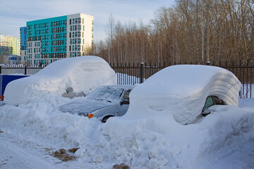 Cars in a street parking lot covered in snow