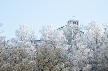 Kirchturm katholische St. Pauluskirche in Neckartenzlingen hinter frostbedeckten B&auml;umen