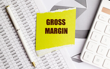 Fototapeta premium Yellow note with text gross margin on financial documents with pen and calculator on office desk