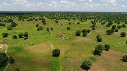 Plan aérien par drone d’une zone rurale en Afrique de l’Ouest, où quelques habitations sont dispersées au milieu de grands espaces naturels.