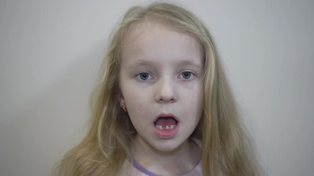 little girl showing her baby teeth that have fallen out, girl showing that she has lost her lower front baby teeth