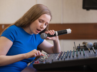 Young woman mixing live sound. Girl recording a song in the studio. 