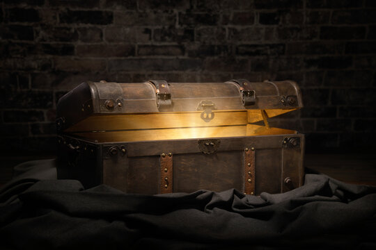 Vintage treasure chest in a dark dungeon opens to reveal a luminous but hidden secret