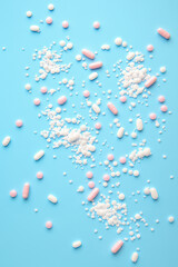 Various pills and powders scattered on a blue background for health and wellness concepts