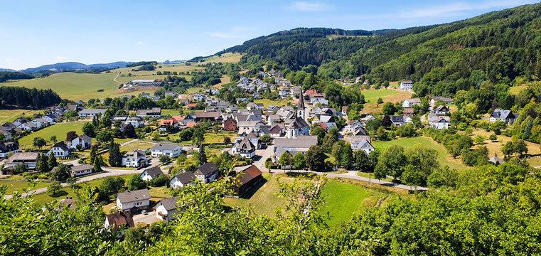 Small town rolling hills landscape from view point with houses, apartments, church, nature hiking forest.