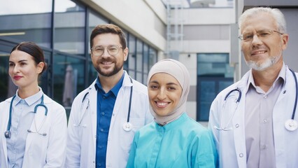 Confident medical staff standing outdoors and holding steady pose while camera moving past group. Focused team maintaining calm expression and presenting unity during professional moment.
