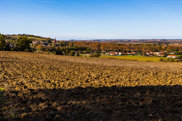 Village of Gardouch in autumn dominated by Saint-Martin Church seen from freshly plowed Lauragais hills