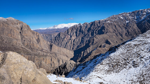 Snow-dusted mountain canyon with rugged rocky slopes under a clear blue sky, showcasing remote wilderness, winter landscape, and dramatic natural terrain.
📍Hawraman Takht, Kurdistan 